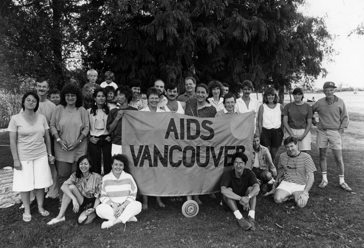 Group of staff and volunteers gathered around an AIDS Vancouver banner at an August 1988 picnic.